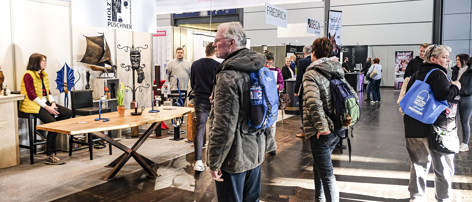 interessierte Besucher am Handwerks-Stand \"Kunstschmiede\", auf einem antiken Tisch sind Schmiedearbeiten ausgestellt