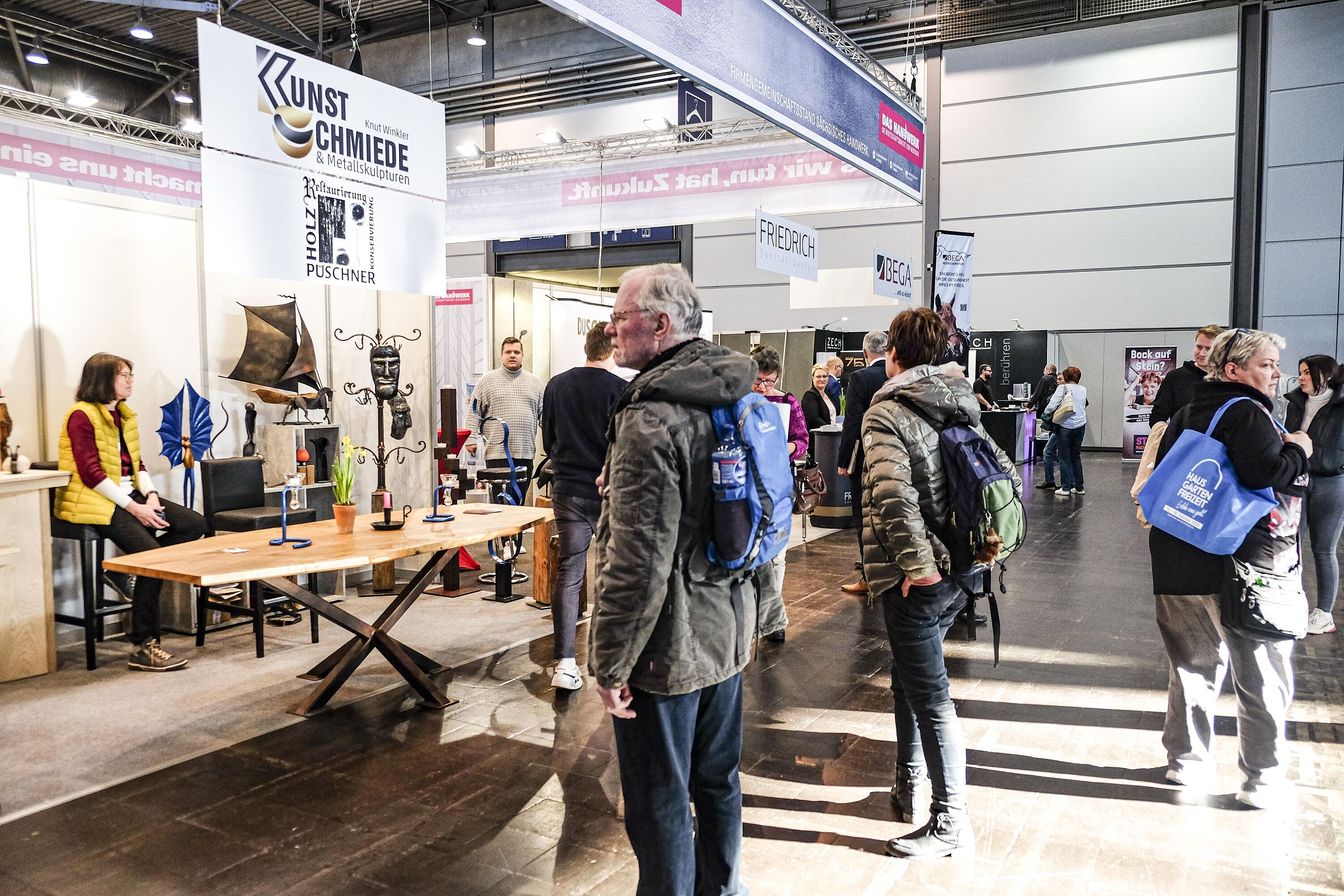 interessierte Besucher am Handwerks-Stand \"Kunstschmiede\", auf einem antiken Tisch sind Schmiedearbeiten ausgestellt