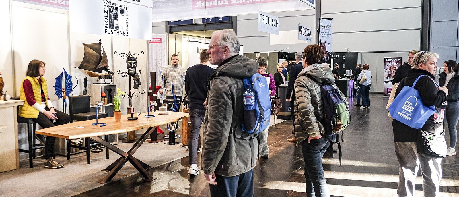 interessierte Besucher am Handwerks-Stand \"Kunstschmiede\", auf einem antiken Tisch sind Schmiedearbeiten ausgestellt