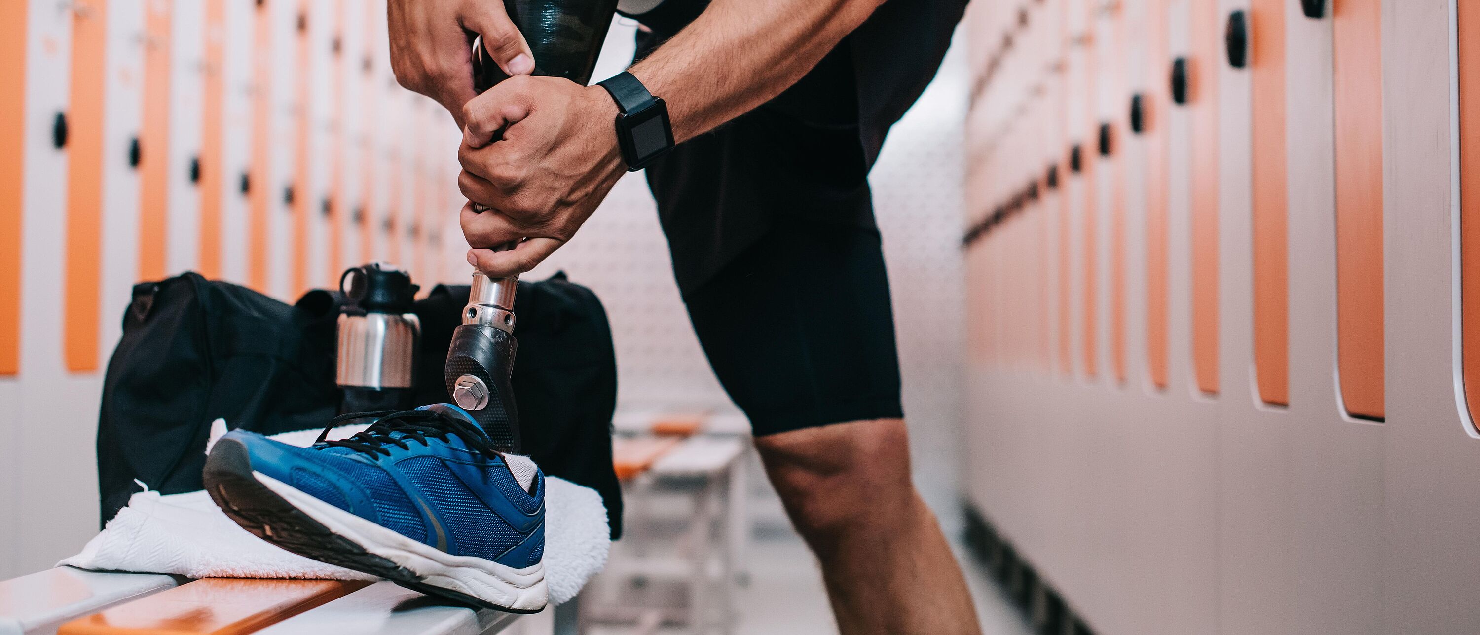 Nahaufnahme eines Sportlers, der in der Umkleidekabine im Fitnessstudio eine Beinprothese anzieht