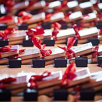 aufgereihte Bücher mit einer roten Geschenkschleife als Geschenk verpackt liegen auf einem Tisch