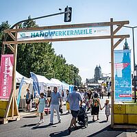 Blick auf den Eingangsbereich zu einem Dresdner Stadtfest der \"Handwerkermeile\". Dieser ist mit regionalen Motiven der Imagekampagne umrahmt \"Handwerk – nicht ohne Innung!\"