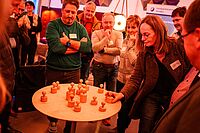 Impressionen vom Workshops wurden im Rahmen der Auftaktveranstaltung Selbstständig Lausitz – mehrere Personen stehen um einen Tisch auf dem sich eine Art Schachfiguren befinden, eine Person referiert dazu.