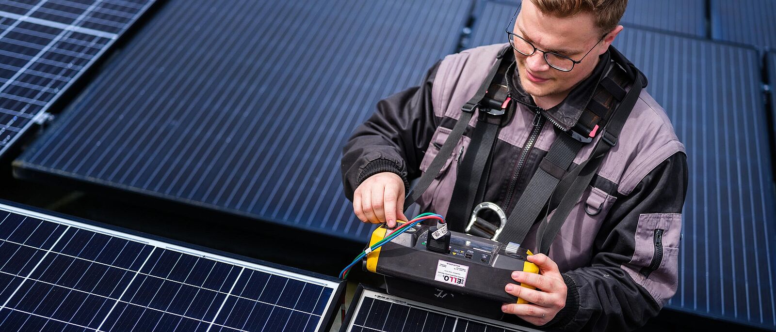 Impressionen vom Insidertreff – Eine Person steht steht zwischen mehreren Solarpanel und führt technische Prüfungen durch.