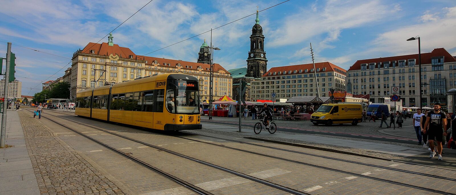 Eine gelbe Straßenbahn, der Verkehrsbetriebe Dresden steht an einer Haltestelle (\"Altmarkt\", stadtauswärts) in der Dresdner Innenstadt.